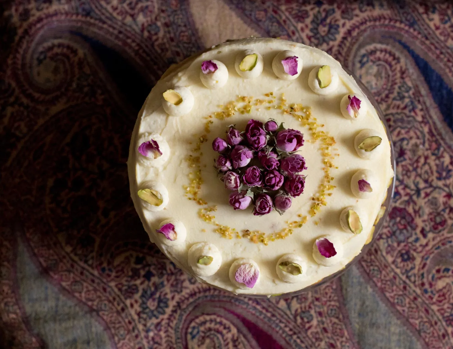 Festlicher Geburtstagskuchen mit Rosen und Pistaziencreme, elegant dekoriert.