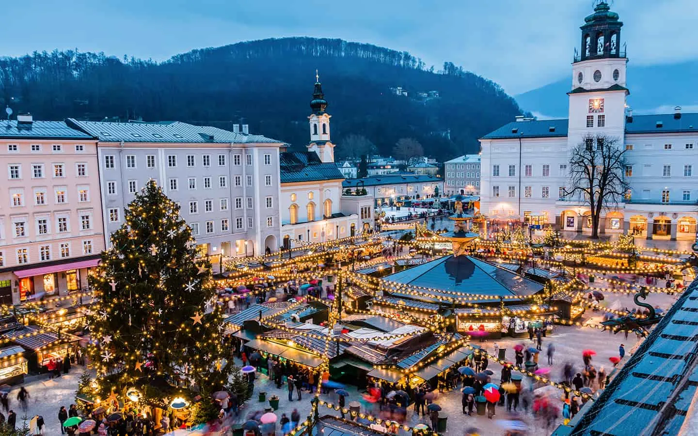 Festlicher Salzburger Weihnachtsmarkt vor beleuchteter Altstadtkulisse, ideal für Winterreisen in Österreich.