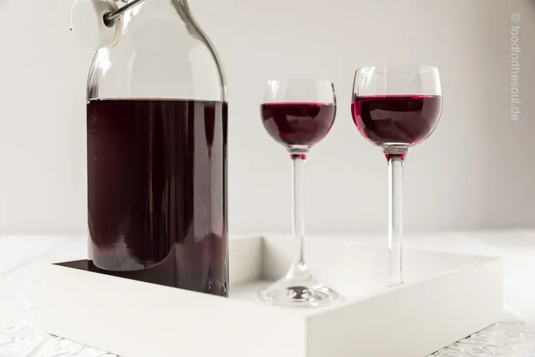 Flasche mit selbstgemachtem Traubenlikör und frischen dunklen Weintrauben, ideal für ein Geschenk