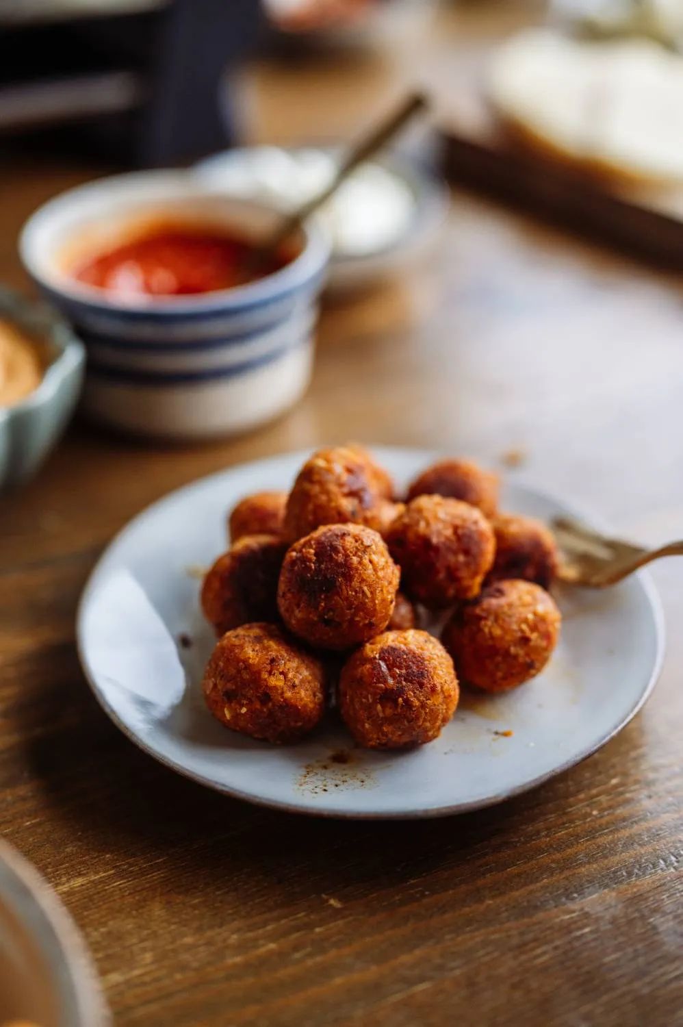 Fleischspieße und Gemüsestreifen brutzeln auf der oberen Grillplatte des Raclette-Geräts
