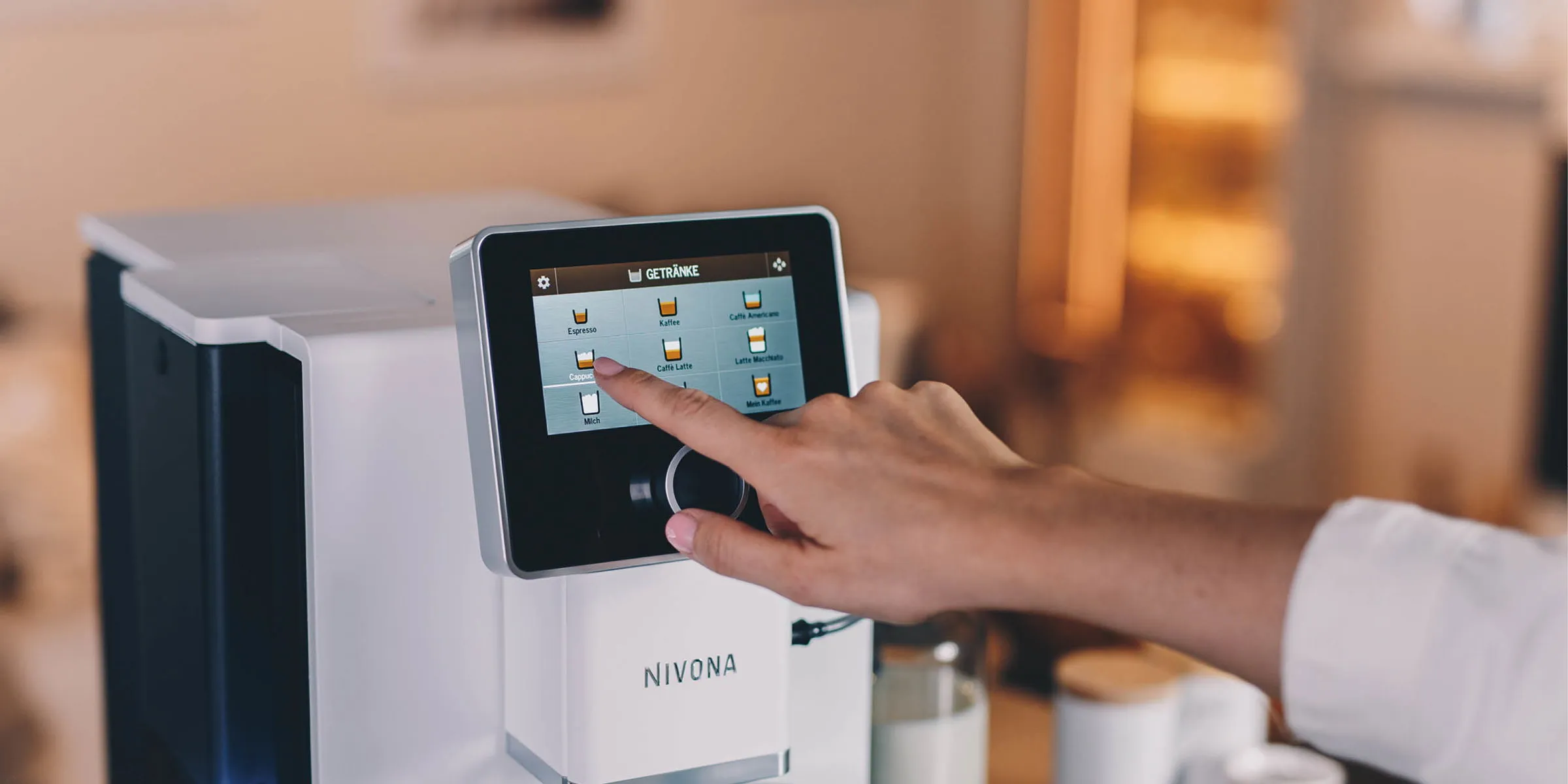 Frau bedient das große Touch-Display einer weißen Nivona NICR 965 Kaffeemaschine mit intuitiven Symbolen