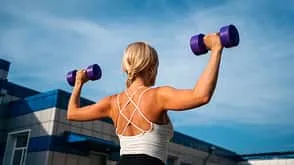 Frau beim Krafttraining mit Hanteln im Fitnessstudio