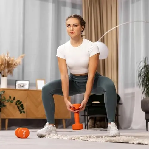 Frau in weißem Shirt und Leggings macht eine Kniebeuge mit einer orangefarbenen Hop-Sport Hantel