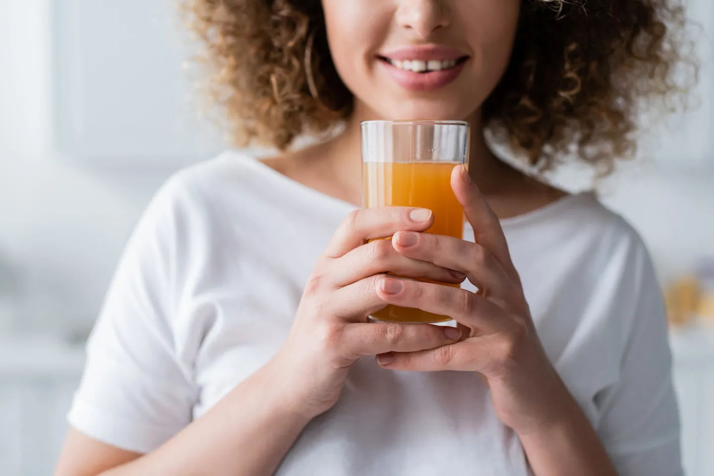 Frau mit Locken hält Glas mit Orangensaft