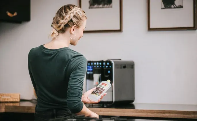 Frau mit Melitta® Entkalker, Hintergrund: Melitta Barista TS Smart