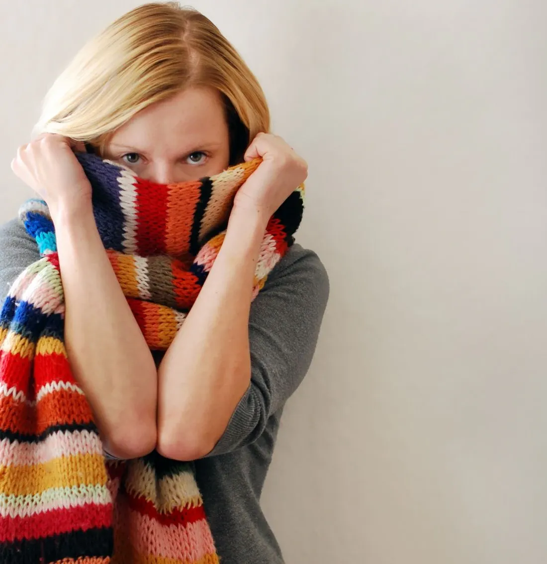Frau schnäuzt sich die Nase mit einem Taschentuch, als Symptom einer Erkältung.