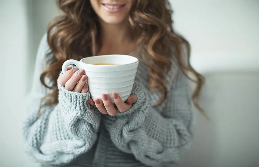 Frau trinkt beruhigenden Kamillentee bei Durchfall, um den Flüssigkeitshaushalt aufzufüllen und den Magen-Darm-Trakt zu schonen.