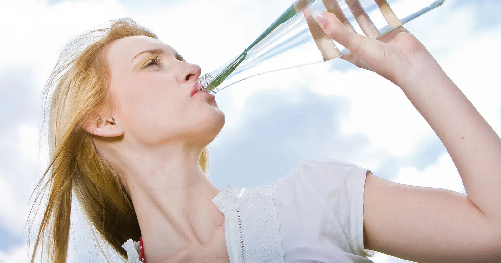 Frau trinkt stilles Wasser als Hausmittel bei Sodbrennen.