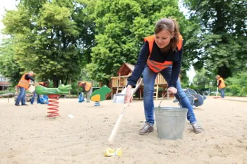 Freiwillige &quot;Kehrenbürger&quot; der BSR sammeln Müll in einem Berliner Park, tragen Warnwesten und Handschuhe