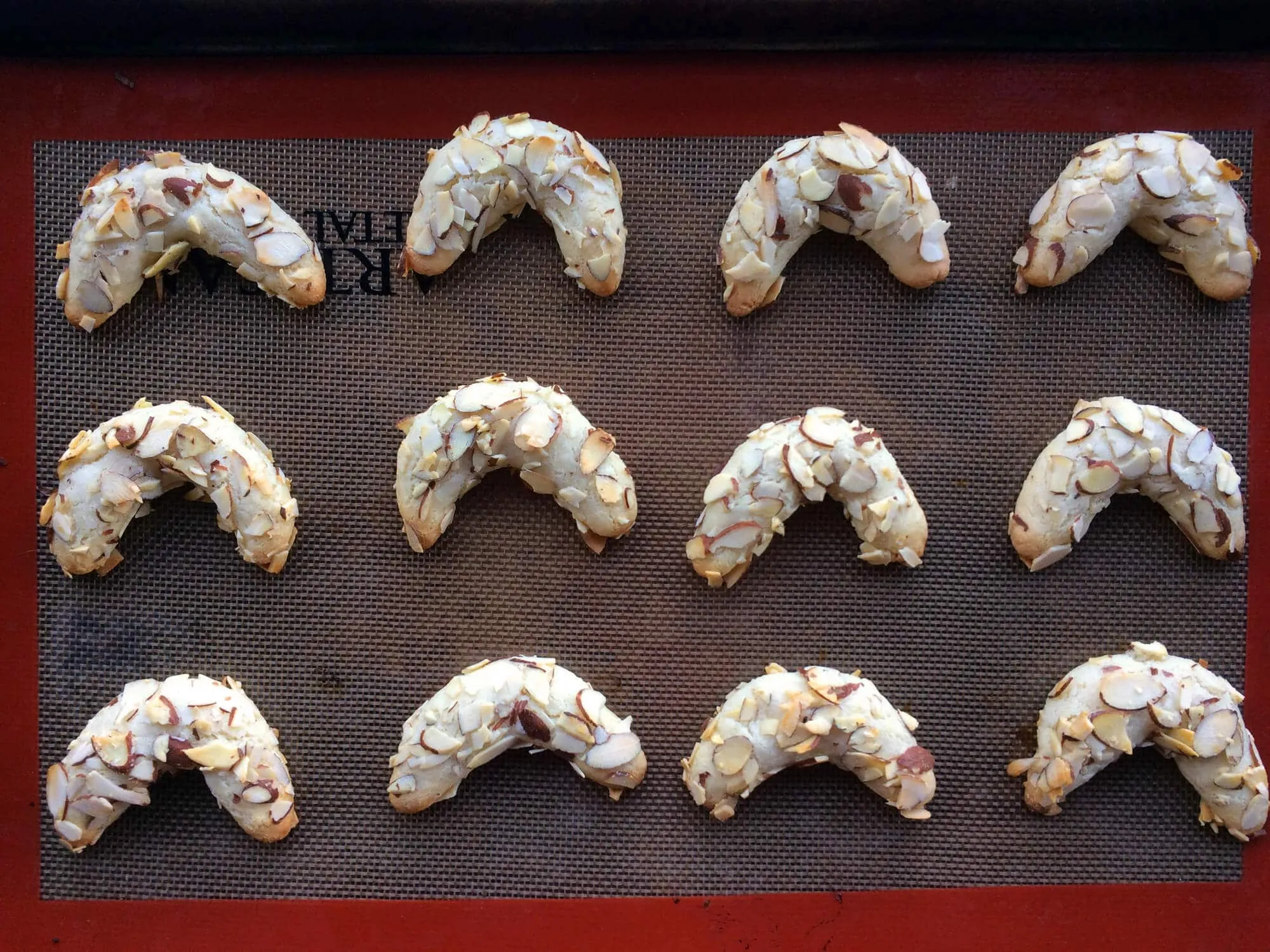 Frisch gebackene Mandelhörnchen kühlen auf einem Gitterrost ab, bereit für die Schokoladenummantelung