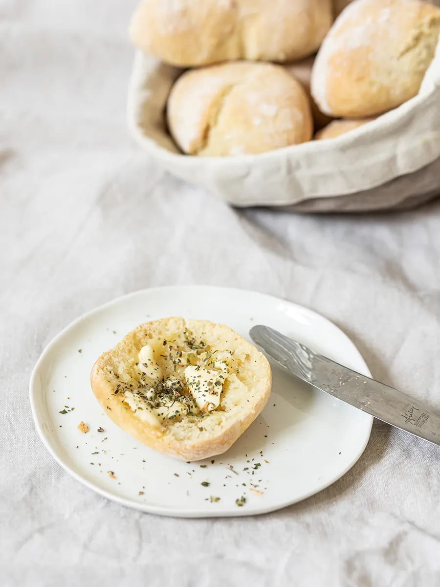 Frisch gebackene mediterrane Brötchen auf einem Holzbrett für das Sonntagsfrühstück