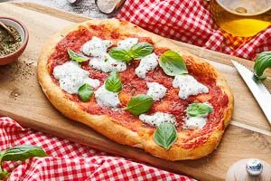 Frisch gebackene Pinsa garnieren und servieren