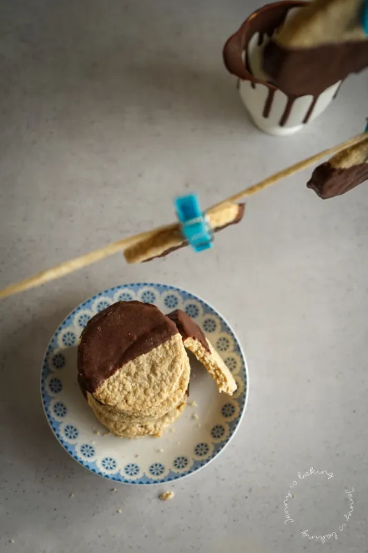 Frisch gebackene, runde Haferflockenkekse mit zartbitterem Schokoladenüberzug, die auf einem Gitter abkühlen