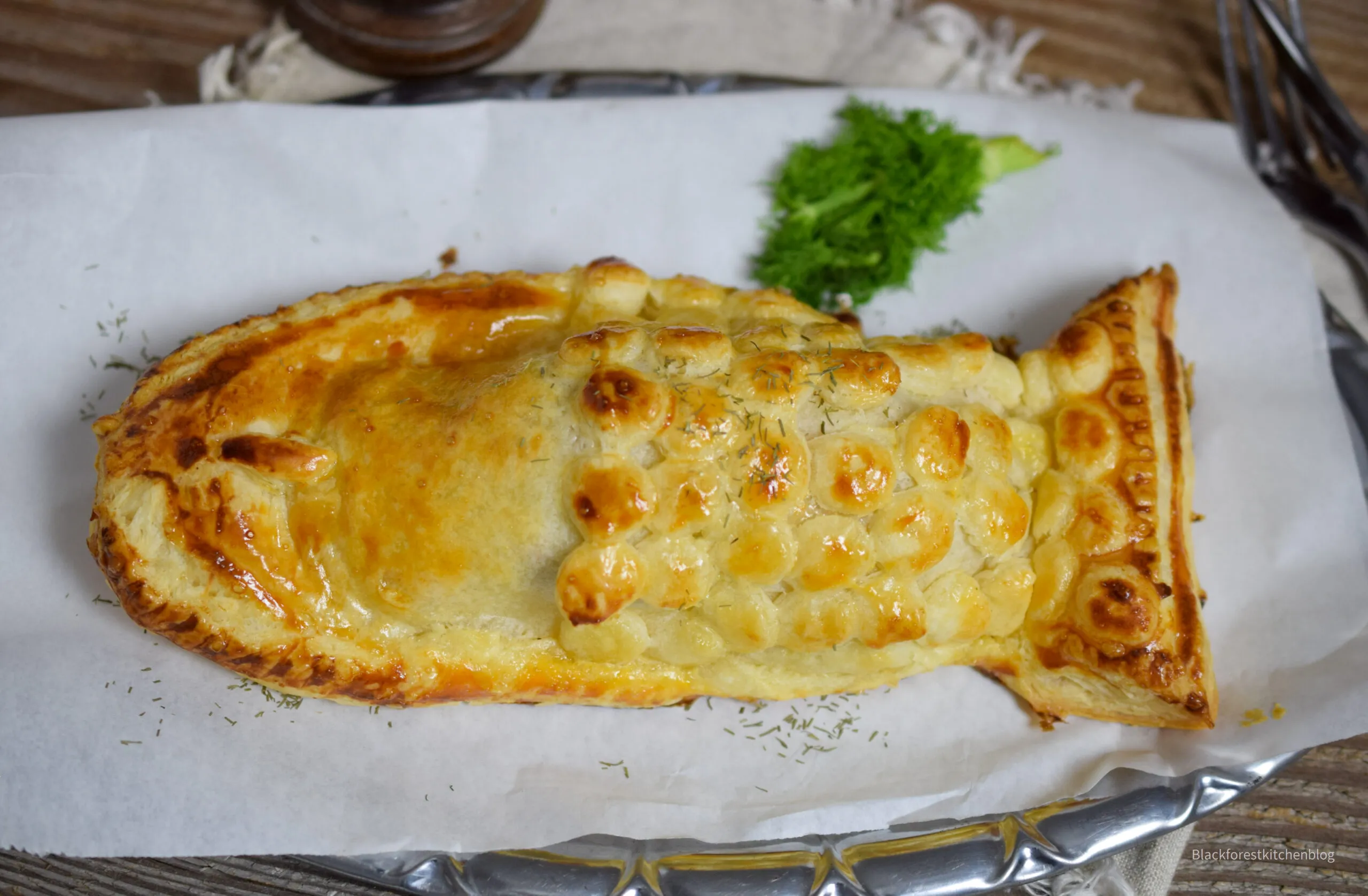 Frisch gebackener Lachs im Blätterteig, goldbraun und knusprig, appetitlich auf dem Backblech nach dem Ofen