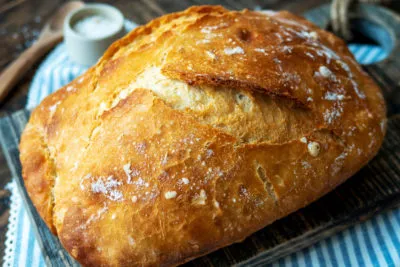 Frisch gebackenes Dinkelbrot auf einem Holzbrett mit einer Scheibe Butter