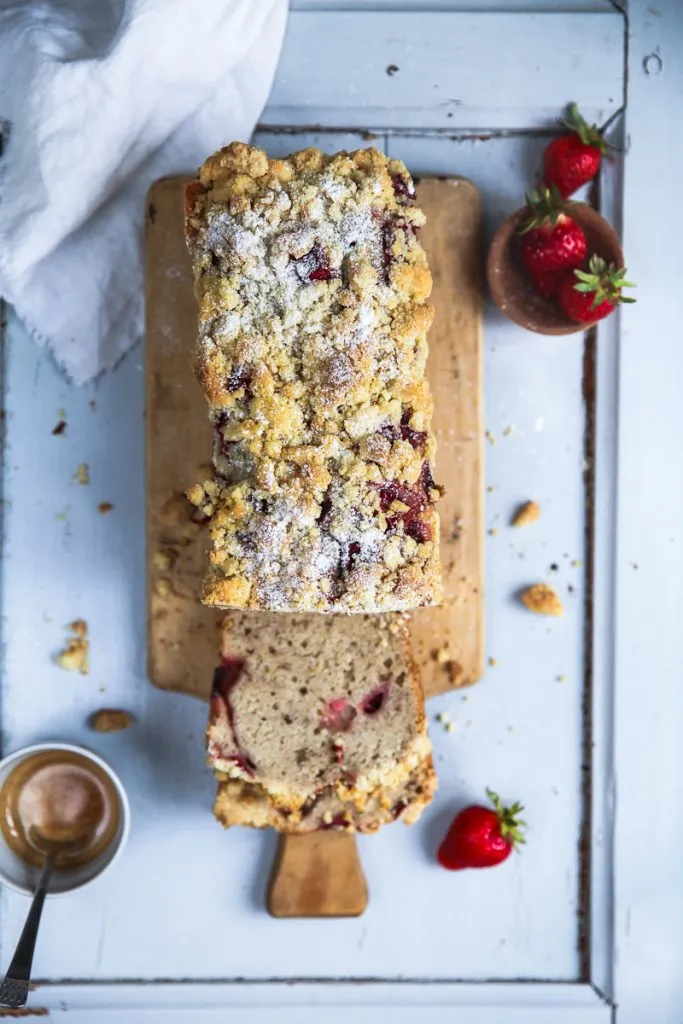 Frisch gebackenes Erdbeer-Bananenbrot in einer Kastenform, bedeckt mit goldenen Zucker-Zimt-Streuseln und saftigen Erdbeeren. Ein einfaches Kuchenrezept für zu Hause.