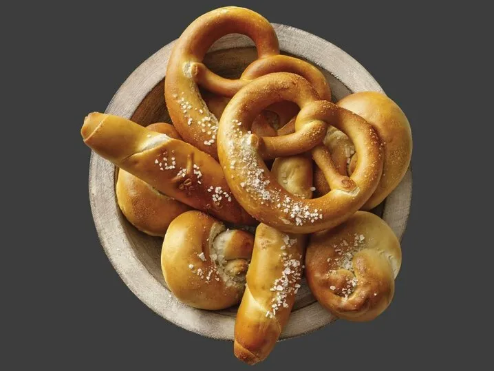 Frisch gebackenes goldenes Laugengebäck, bestehend aus knusprigen Brezeln, Stangen und Knoten, appetitlich angerichtet für eine traditionelle deutsche Brotzeit.