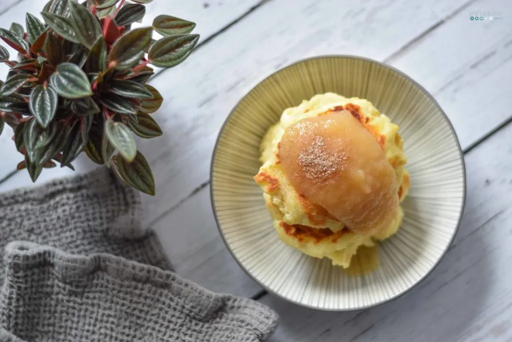 Frisch gebratene Sächsische Quarkkeulchen in der Pfanne, servierfertig mit Zimtzucker und Apfelmus.