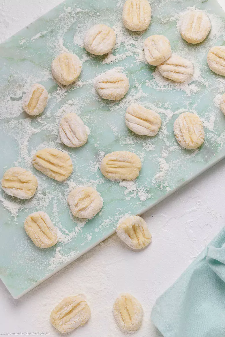 Frisch geformte Kartoffelgnocchi auf einem Holzbrett, bereit zum Kochen oder Einfrieren nach einem einfachen Rezept.