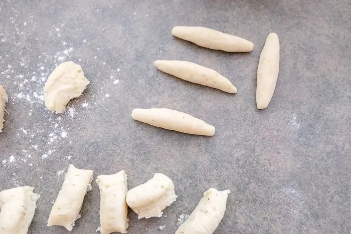 Frisch geformte Schupfnudeln, einzeln gerollt aus Kartoffelteig auf einer bemehlten Küchenzeile