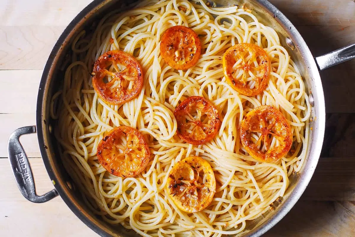 Frisch gekochte Spaghetti werden in der Pfanne mit der aromatischen Zitronen-Knoblauch-Butter-Soße vermengt.