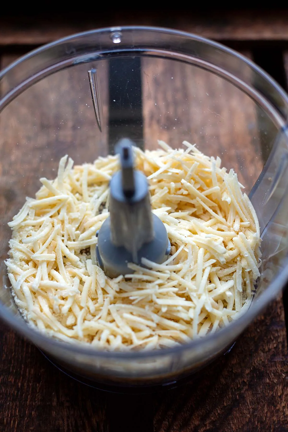 Frisch geriebener Parmesan in einer Küchenmaschine, perfekt für eine cremige Käse-Sahne-Soße.