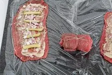 Frisch gerollte Rinderroulade, fest mit Küchengarn fixiert, um die Füllung beim Schmoren zu bewahren.