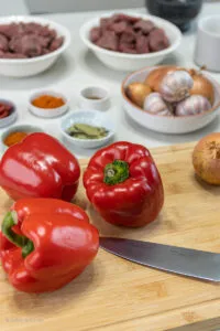 Frisch geschnittene rote Paprikawürfel und Zwiebeln, wichtige Zutaten für ein aromatisches ungarisches Gulasch.