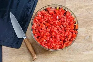 Frisch gewürfelte Tomaten werden als Schicht auf die Kidneybohnen im Taco Salat verteilt.