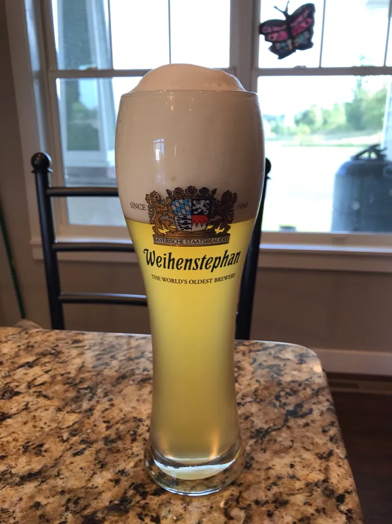 Frisch gezapftes, trübes deutsches Hefeweizen in einem Weizenglas, das die typische Farbe und den Schaum zeigt