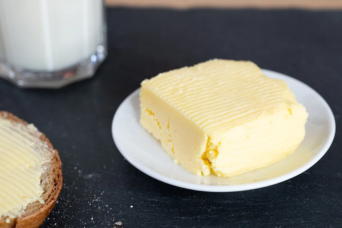 Frisch zubereitete Butter aus Milch in einer rustikalen Schüssel, perfekt zum Butter selber machen zu Hause.