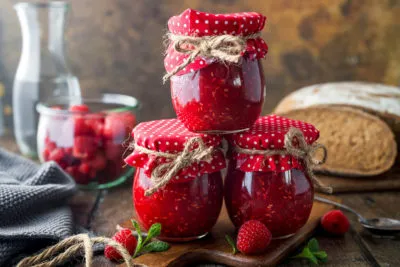 Frisch zubereitete Himbeermarmelade in sterilisierten Einmachgläsern, bereit für den Vorratsschrank.