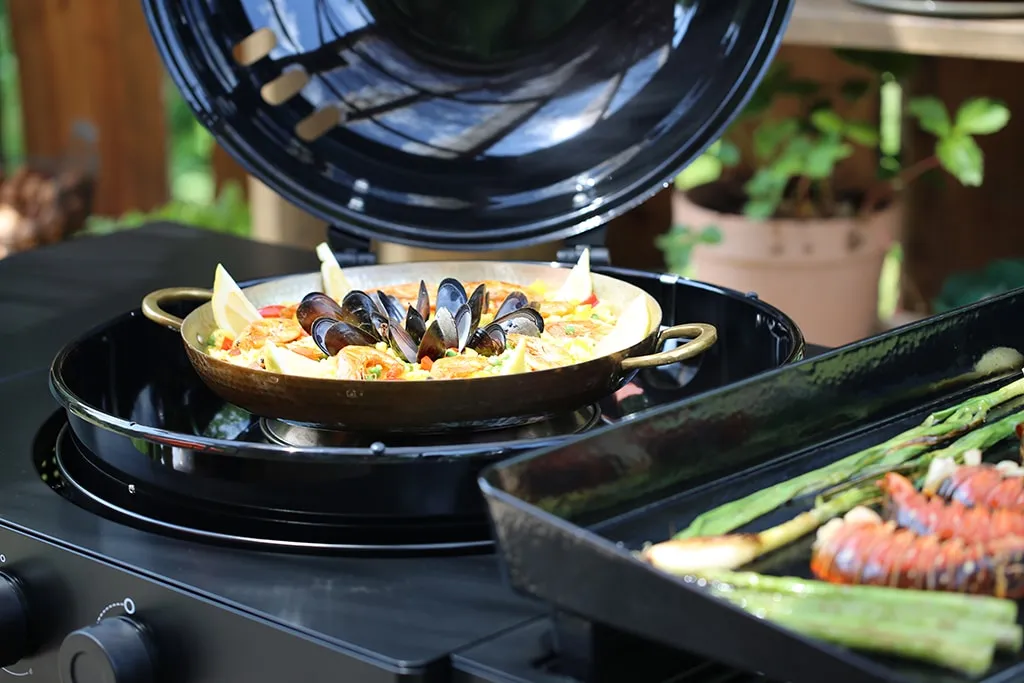 Frisch zubereitete Paella mit Meeresfrüchten in einer Paellapfanne, garniert mit Zitronenspalten, bereit zum Servieren.