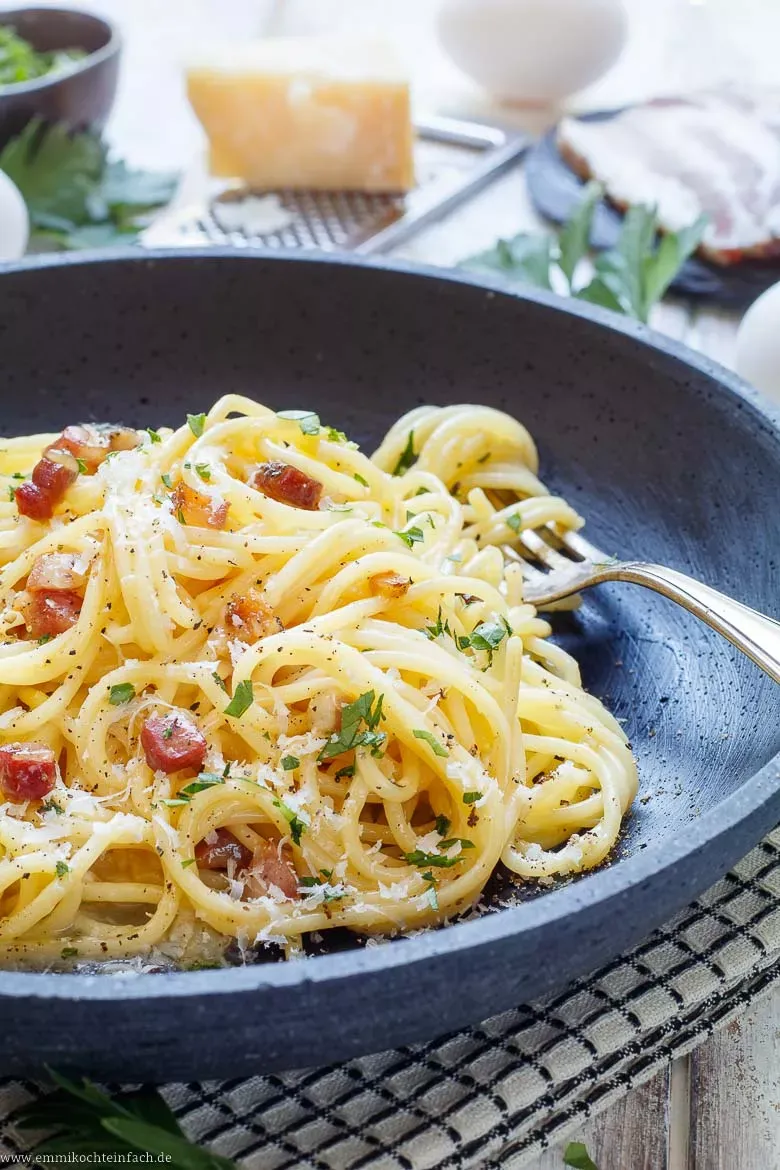Frisch zubereitete Spaghetti Carbonara auf einem Teller, garniert mit frischem Pfeffer und Petersilie, ein einfaches aber exquisites Rezept.