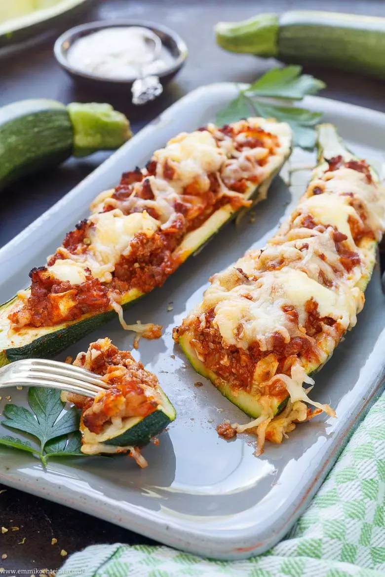 Frisch zubereitete Zucchini Schiffchen, gefüllt mit herzhafter Hackfleisch-Tomatensauce, bereit für den Backofen.