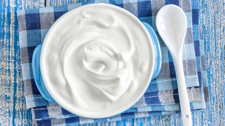 Frisch zubereiteter, cremiger Quark in einer blauen Keramikschüssel mit einem Löffel, bereit zum Genuss oder zur Weiterverarbeitung.