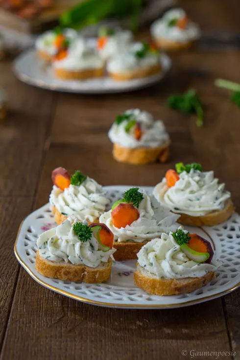 Frisch zubereiteter Frühlingskräuter-Aufstrich mit frischen Kräutern in einer weißen Schale auf rustikalem Holzuntergrund