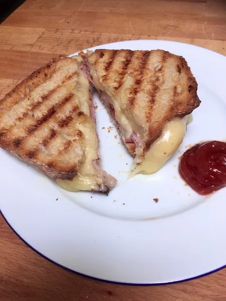Frisch zubereiteter goldbrauner Schinken-Käse-Toast, angeschnitten mit geschmolzenem Käse
