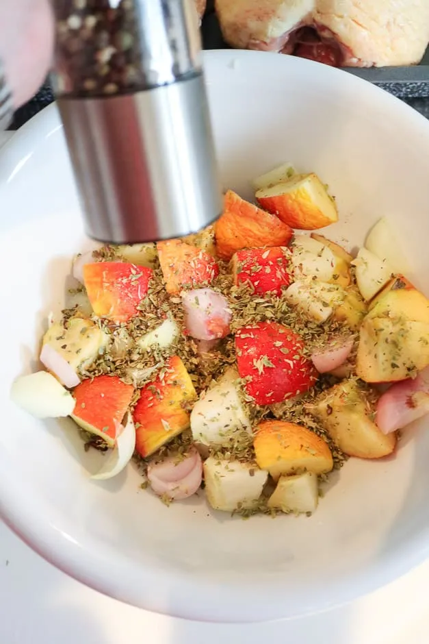 Frische Apfel- und Zwiebelviertel in einer Schüssel, gewürzt mit Majoran für die Gänsefüllung.