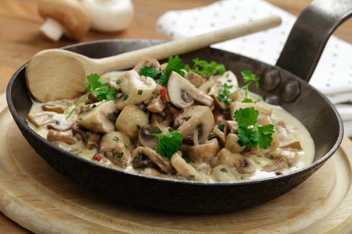 Frische cremige Pilzpfanne mit gebratenen Champignons und Petersilie in der Pfanne