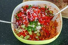 Frische Gemüsezutaten werden unter den gequollenen Bulgur gemischt