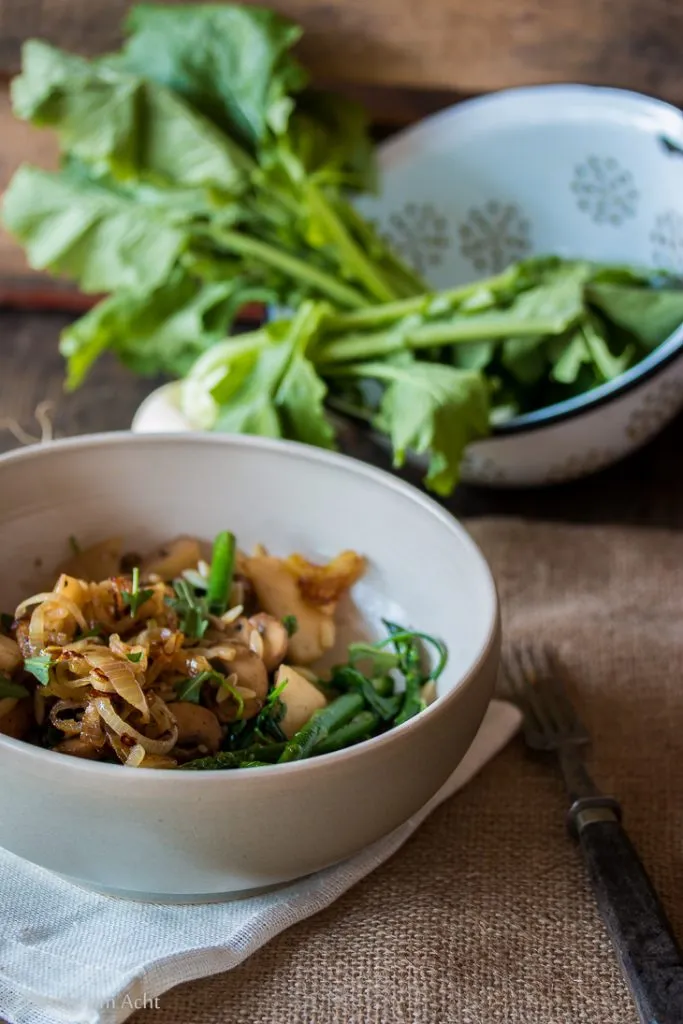 Frische Orzo-Nudeln mit zarten Mairübchen, gebratenen Champignons und grünem Spargel auf einem Teller angerichtet