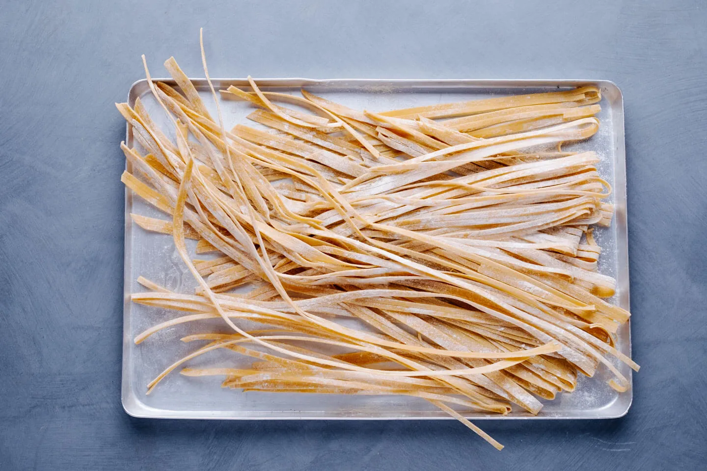 Frische Tagliatelle hängen zum Trocknen über einem Stab
