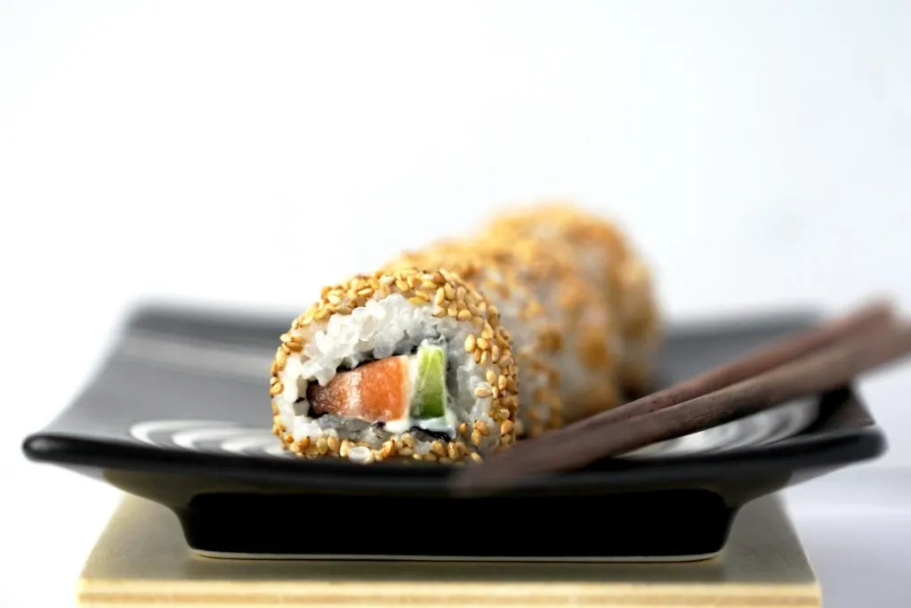 Frische Uramaki Inside-Out Sushi Rolls, auch bekannt als California Rolls, mit Sesam bestreut