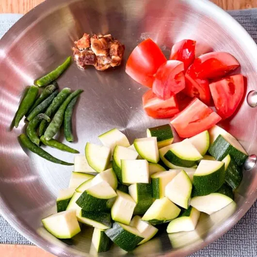 Frische Zutaten für ein selbstgemachtes Zucchini-Chutney, darunter Zucchini, Tomaten und Chilis