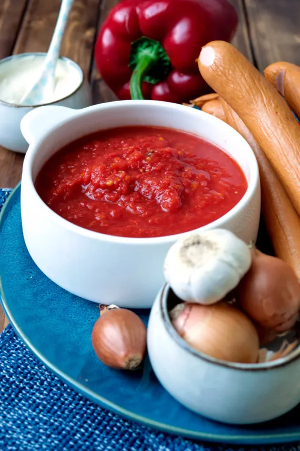 Frische Zutaten für Würstchengulasch: Gehackte Tomaten, geschnittene Wiener Würstchen, Paprika und Zwiebeln