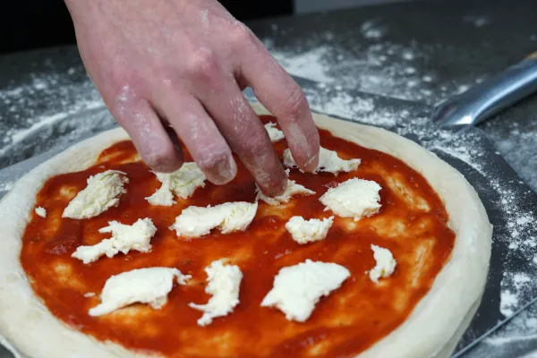 Frischen Mozzarella auf der Pizza Margherita verteilen
