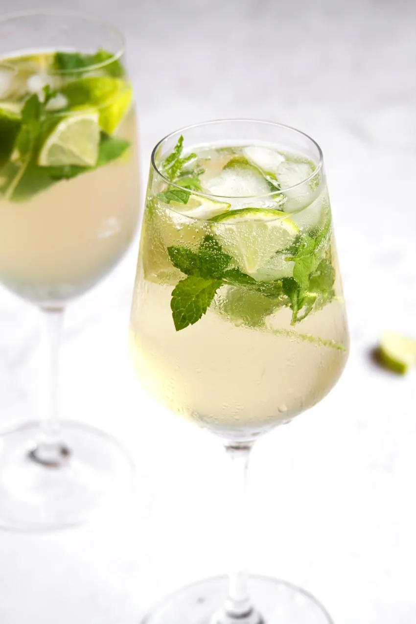 Frischer Hugo Cocktail in einem Weinglas mit Minze und Limettenscheiben, bereit zum Genuss