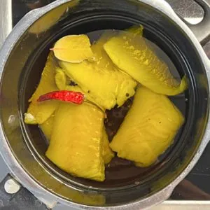 Frischer Kabeljau in einer Auflaufform, bereit zum Konfieren in Olivenöl mit Lorbeerblättern und Chili.