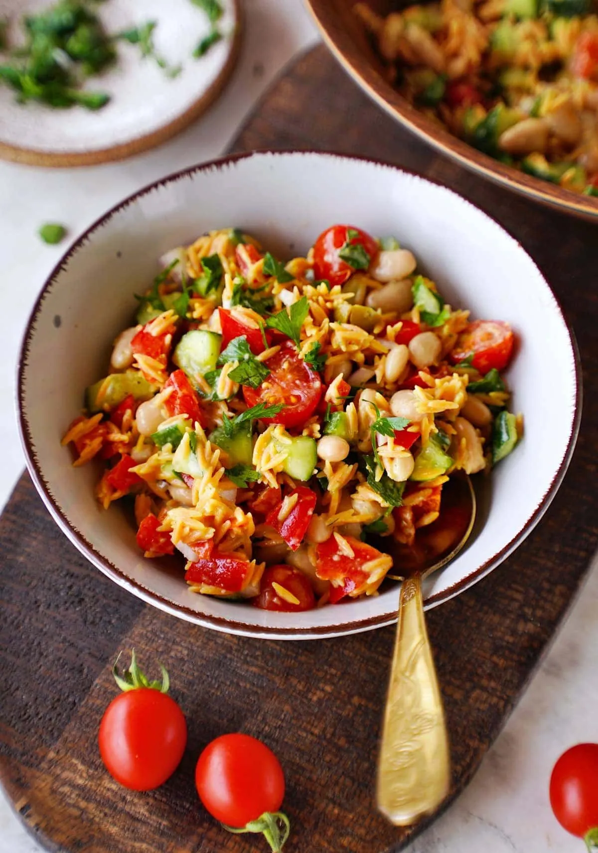 Frischer mediterraner Orzo-Salat mit weißen Bohnen und Zitronenvinaigrette in einer weißen Schale, perfekt als leichtes veganes Mittagessen.